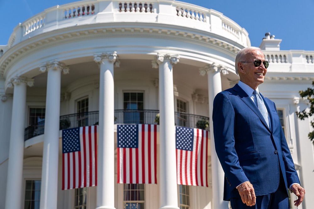 President Joe Biden in sunglasses on the South Lawn of the White House, with American flags hung from the building behind him, before signing the CHIPS and Science Act