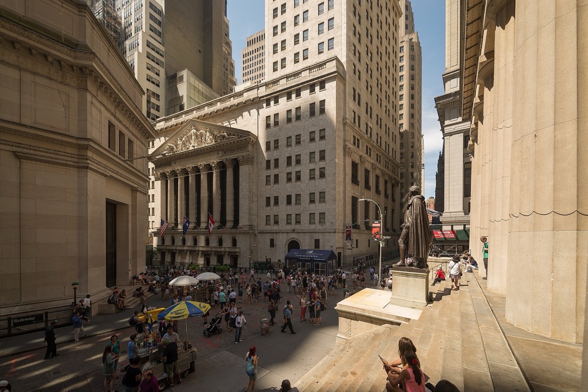 The neoclassical facade of the New York Stock Exchange on Wall Street, hung with a large American flag