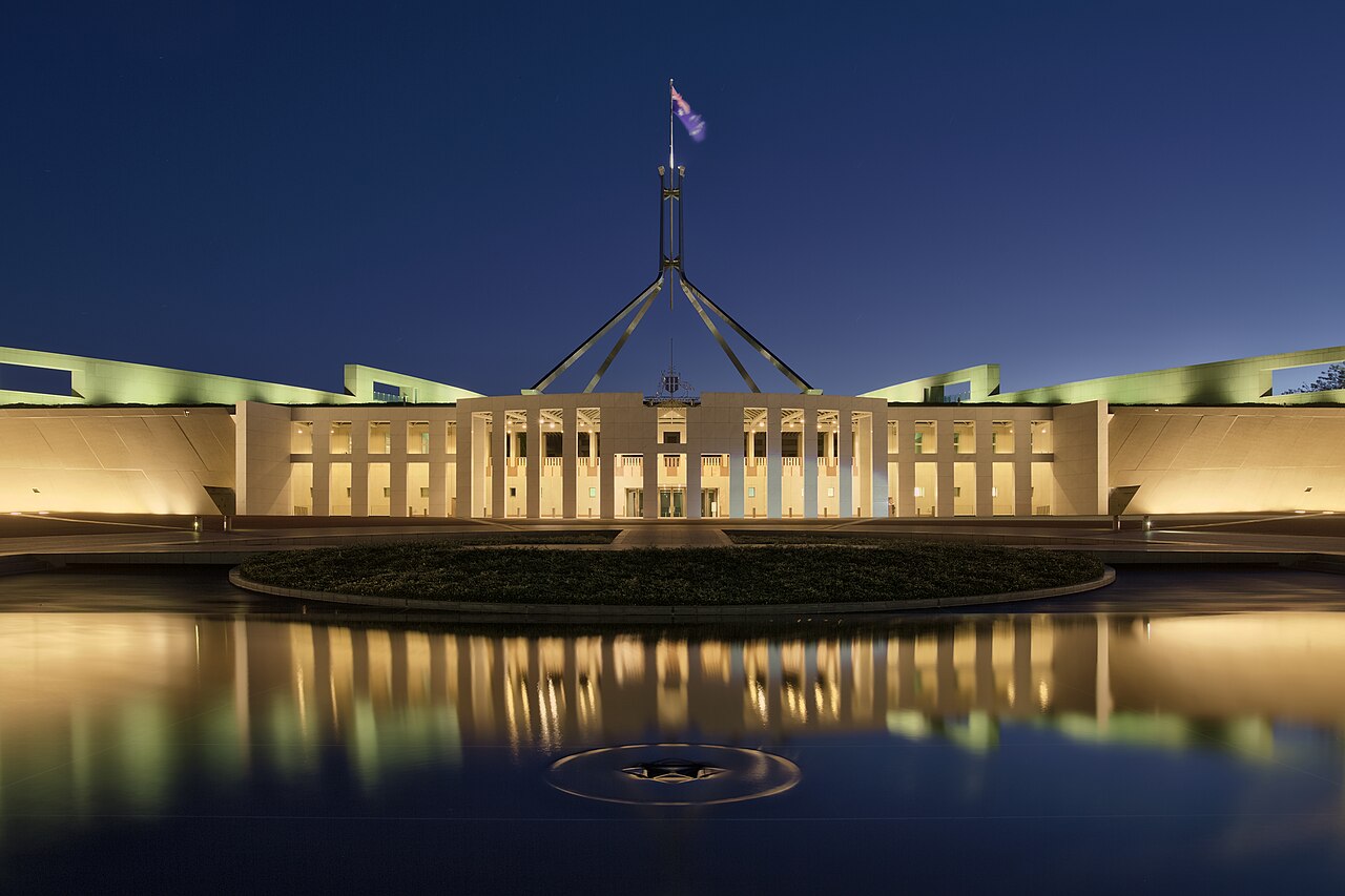 Parliament House in Canberra at dusk, lit against a darkening sky
