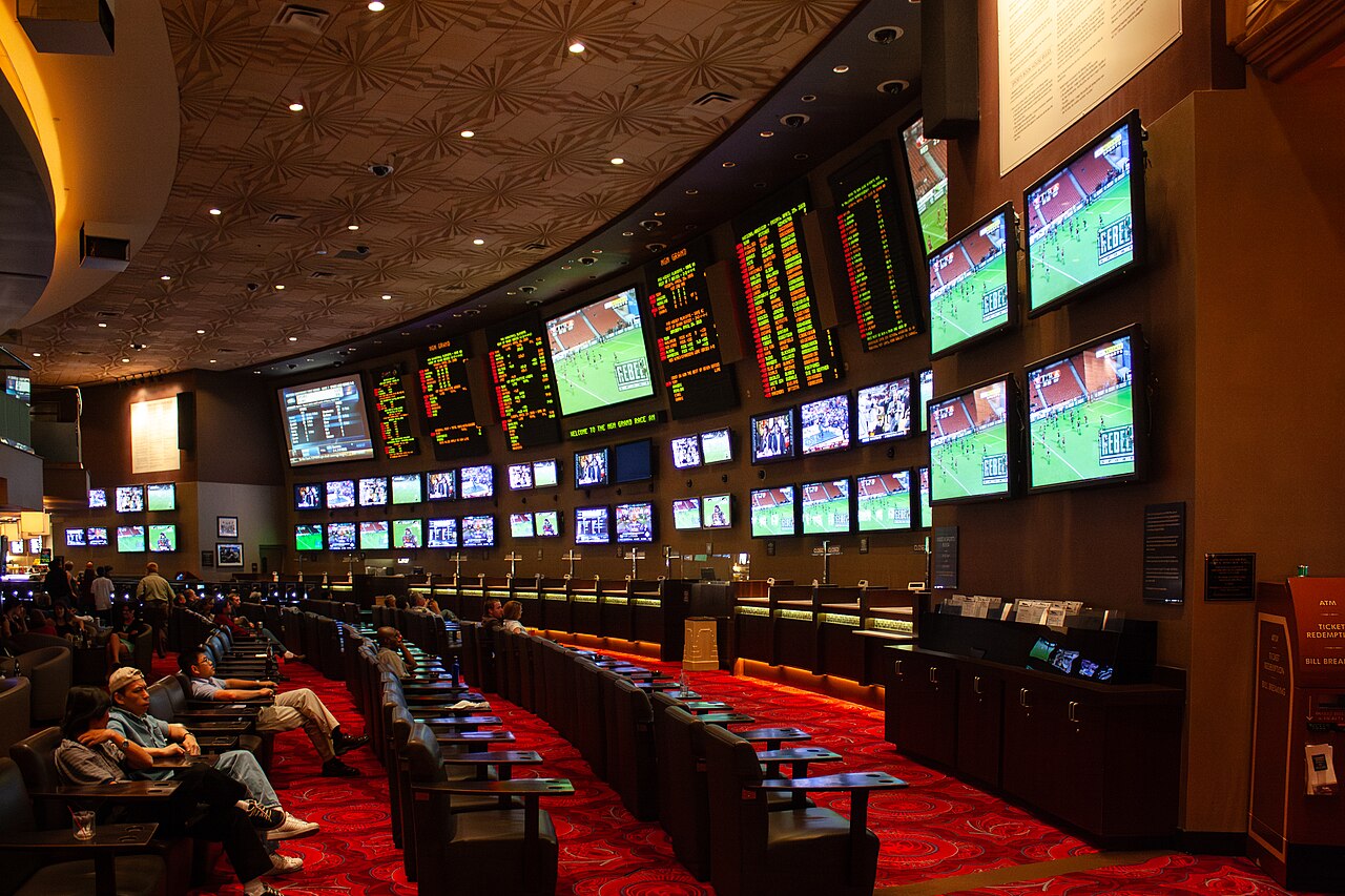 Walls of screens showing live games and betting odds inside a Las Vegas sportsbook